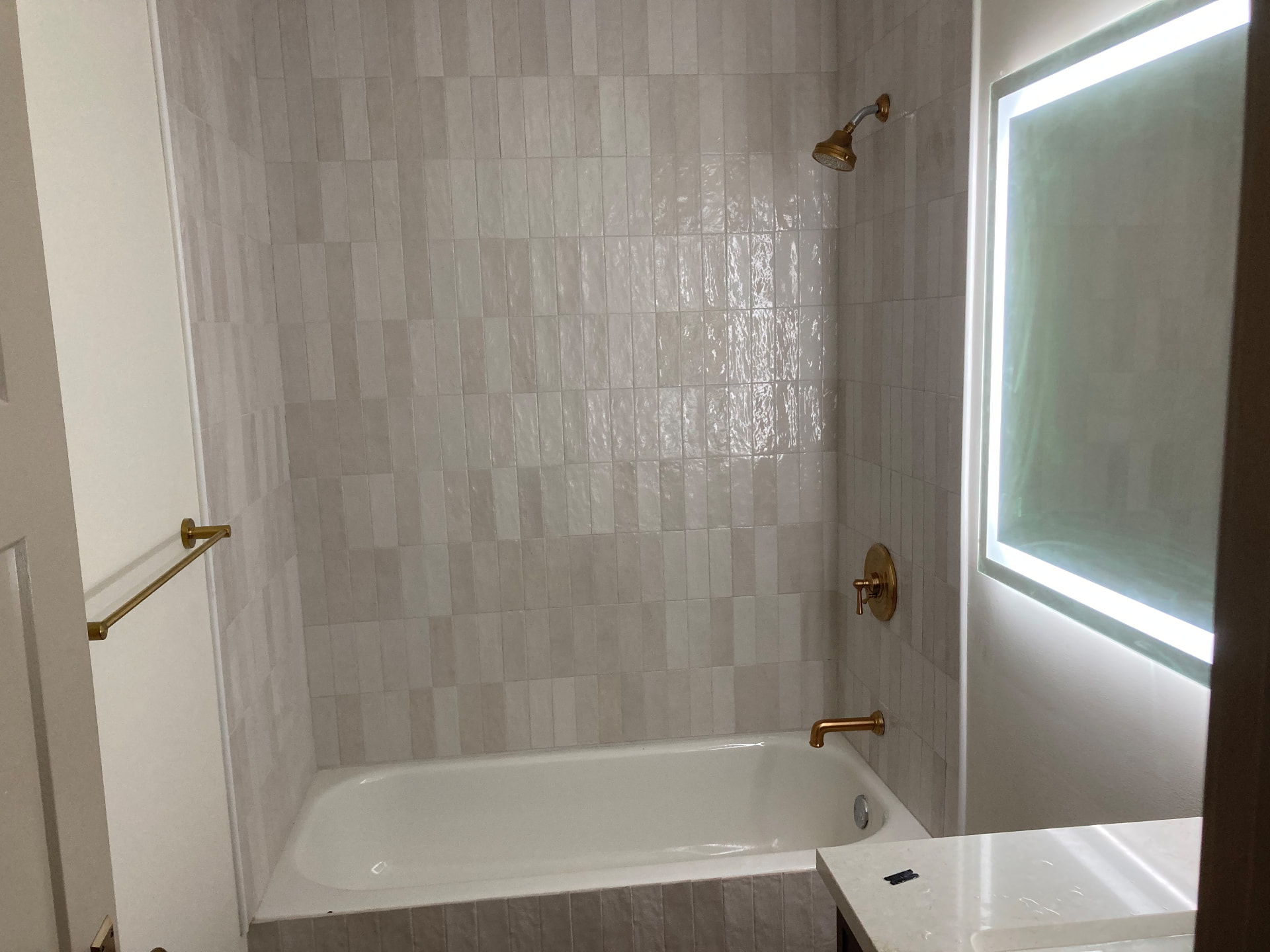Bathroom with glossy vertical tile surround and brass fixtures