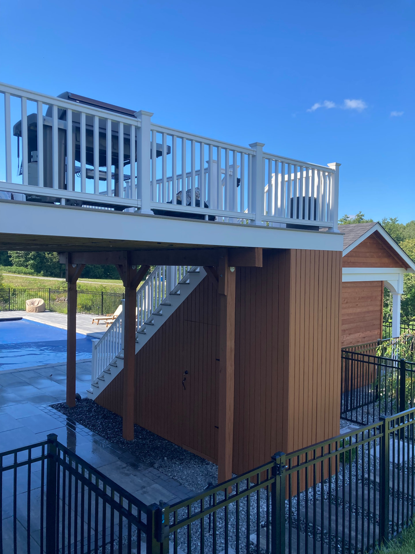 Elevated deck with white railings and stained wood storage enclosure